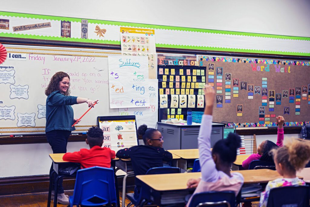 Teacher calling on students with raised hands in a classroom