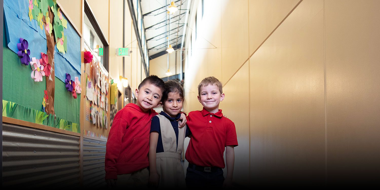 Group of smiling students with their arms around each other in the hallway